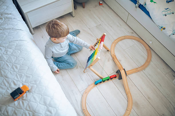 istock Small boy playing with abacus and wooden train at home. 2207910146