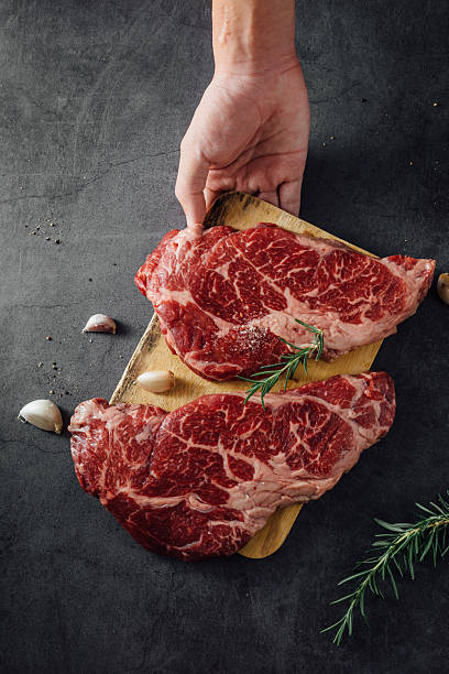 istock Fresh Raw Beef Cuts on Wooden Board with Garlic and Herbs for Culinary Preparation 2207911244