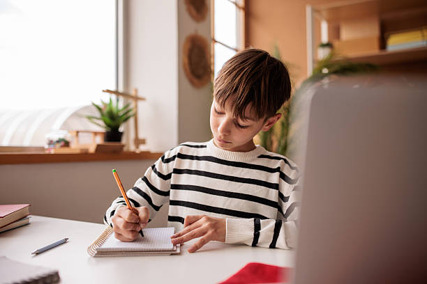 istock Young boy studying at home with the help of a laptop 2207911399