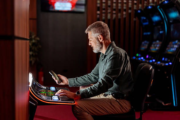 istock Man Playing Slot Machine in Modern Casino Interior 2207911521