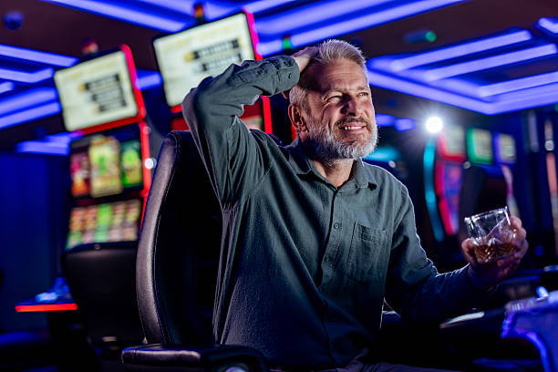 istock Sad Man Sitting with a Drink in a Casino Environment 2207912943