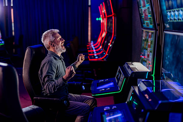 istock Senior Man Celebrating at Gaming Machine in Colorful Casino Setting 2207912978