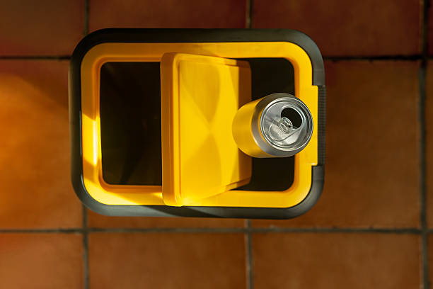 Spain. An aluminum can being discarded into a yellow recycling bin, symbolizing responsible waste management and environmental conservation efforts