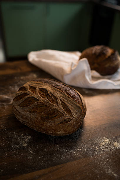 istock Freshly baked sourdough bread loaf showing scoring pattern on wooden table 2207915019