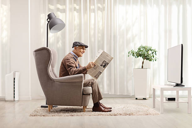 istock Elderly man in an armchair reading a newspaper 2207915776