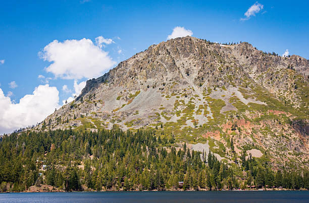 A stunning landscape of Lake Tahoe featuring crystal-clear turquoise water, rustic wooden piers, and snow-capped mountains under a vibrant blue sky.