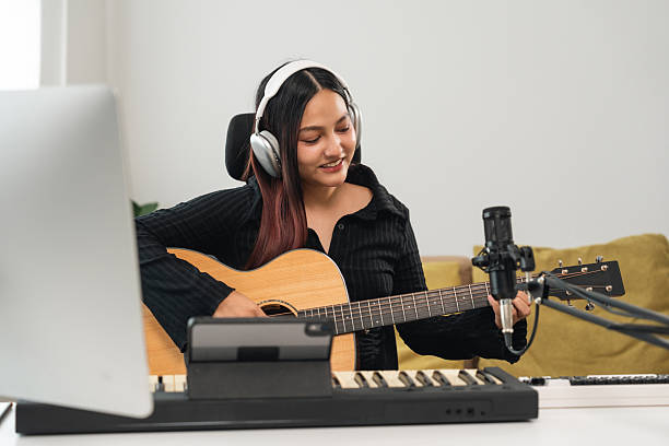istock Professional Musician with condenser microphone and tablet for Mixing Mastering music. Music composer woman composing a song with guitar and piano keyboard at digital Recording home studio 2207919005