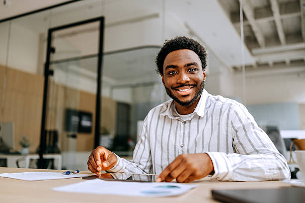 istock Cheerful young businessman posing for the camera while using a digital tablet at the office 2207921325