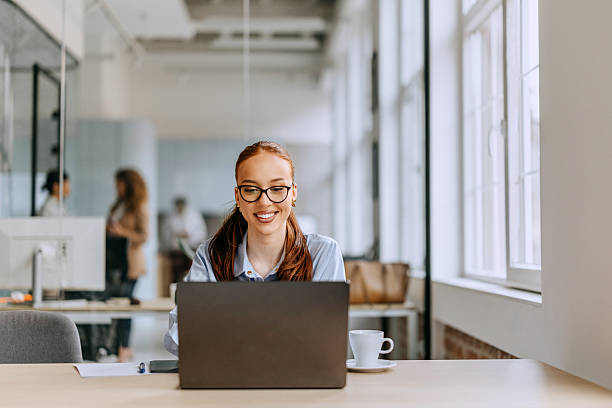 istock Young cheerful businesswoman using laptop at the office 2207921792