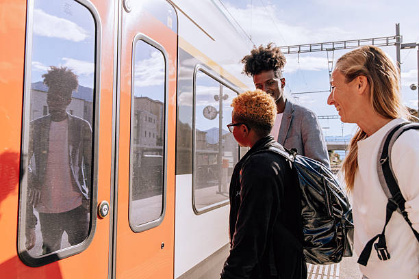 Father, mother, and son preparing to board a train with backpacks. Family travel and commuting on a sunny day. Excited family trip by railway.