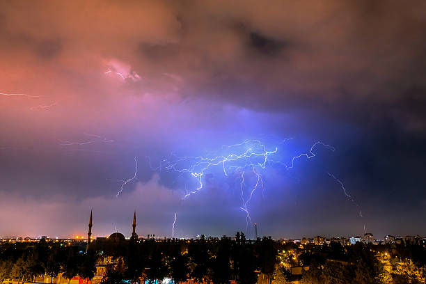 Bright lightning bolts illuminate the evening sky above city buildings, showcasing the beauty and power of nature.