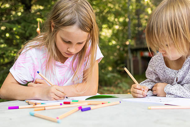 istock Two sisters focused on their artwork in a summer garden 2207923801