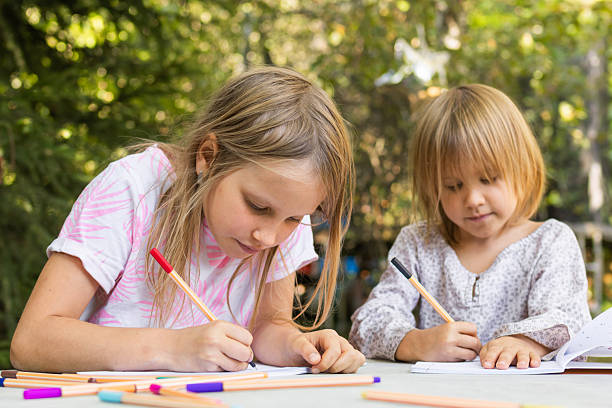 istock Sisters engaged in creative drawing with fineliners in a summer garden 2207923834