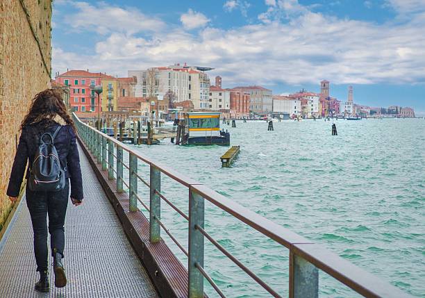 Venice, Italy - 15 March 2025 - The city on the sea, with the most characteristic places and touristic attractions in the world. Here in particular a landmark view: a cityscape with lagoon and girl tourist
