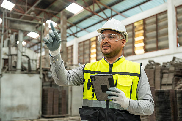 istock Confident engineer man with safety helmet standing analyzing with tablet in factory warehouse. Asian technician factory inspection and control machinery in industry factory. 2207926379