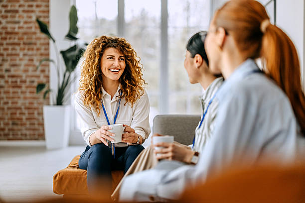 Smiling colleagues casually chatting while sitting on a sofa in the office break room