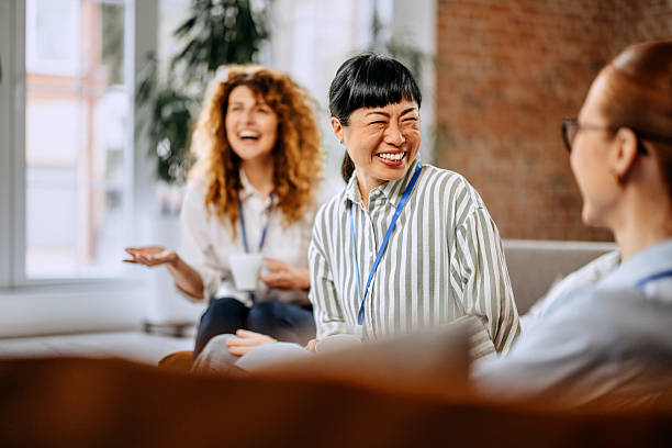 istock Smiling colleagues casually chatting while sitting on a sofa in the office break room 2207926615