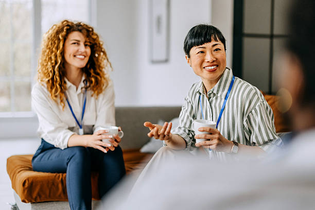 istock Smiling colleagues casually chatting while sitting on a sofa in the office break room 2207927259