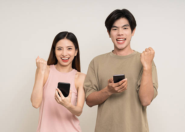 istock Happy asian couple attractive in various action gesture using smartphone standing on isolated white background. Cheerful Smiling young man and woman holding cell phone 2207927834