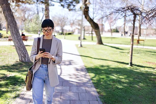istock Teacher looking at her smartphone while walking in the park 2207928711