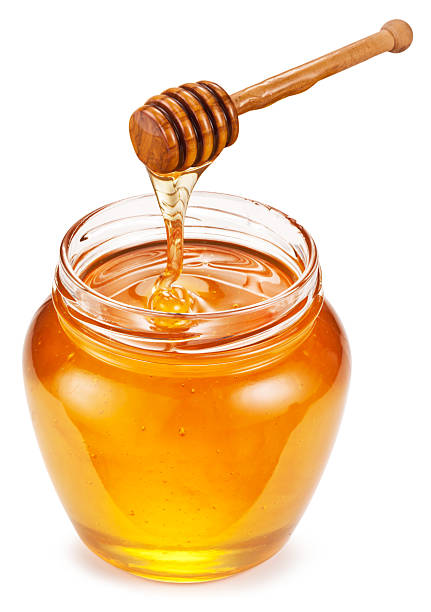 istock Honey dripping from honey spoon into honey pot on white background. File contains clipping path. 2207928849