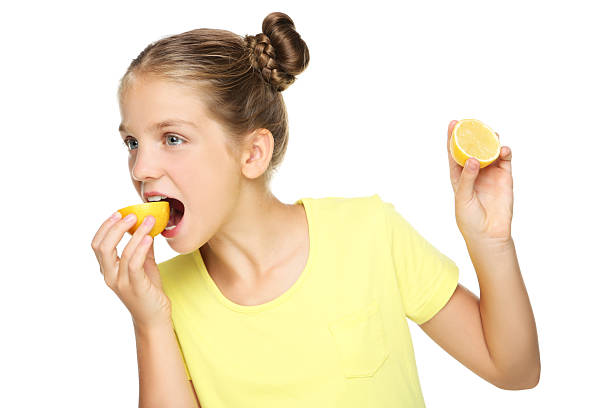 istock Young girl eating lemon fruit on white background 2207930663