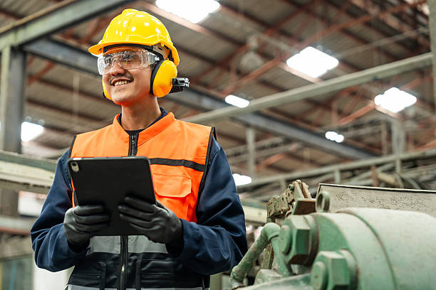 istock Confident engineer man with safety helmet standing analyzing with tablet in factory warehouse. Asian technician factory inspection and control machinery in industry factory. 2207931190