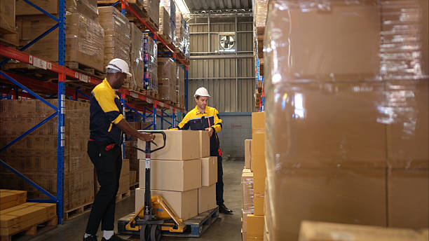 istock Two warehouse workers are lifting boxes of merchandise on a pallet jack to store on a shelf in a warehouse 2207933643