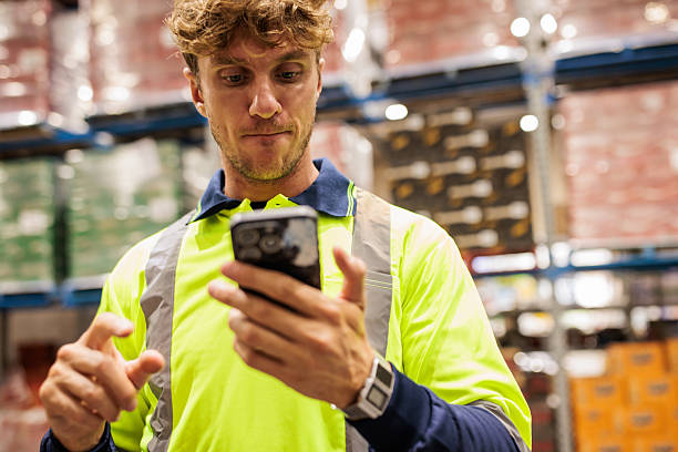 istock Warehouse Worker with Smart Phone Managing Stock 2207934140