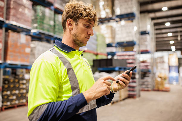istock Warehouse Worker with Smart Phone Managing Stock 2207934160