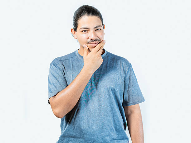 istock Pensive person rubbing chin with doubtful expression. Thoughtful young man rubbing his chin looking at camera isolated 2207935522
