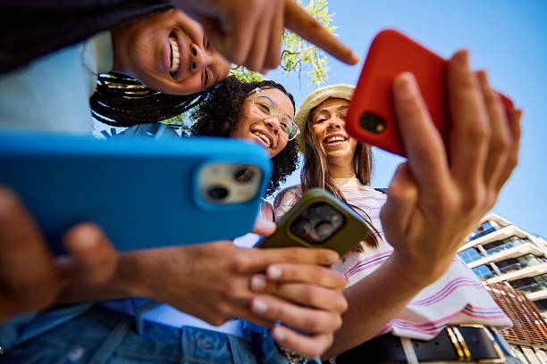 istock Cheerful students sharing a funny video on a smartphone outdoors 2207935532