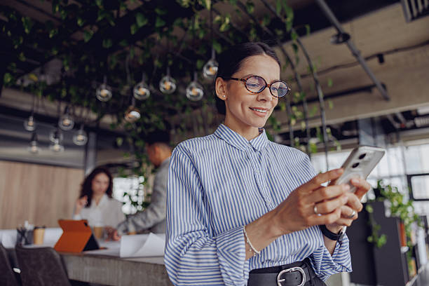 istock A professional woman actively engaged in mobile communication within a modern office space 2207935925