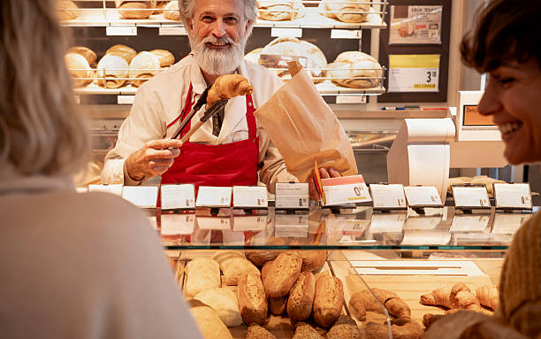 istock Experienced Baker With Gray Beard Serving Fresh Bread At Traditional Bakery Counter 2207936774