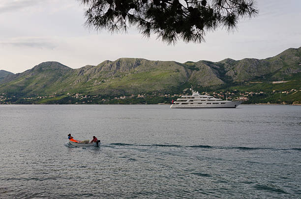 A zodiac boat passes in front of a yacht in the Croatian port of Cavtat