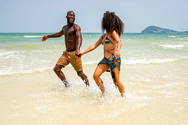 istock Playful Couple Running Hand in Hand on Sunny Beach 2207944182