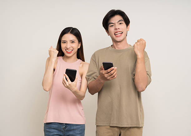 istock Happy asian couple attractive in various action gesture using smartphone standing on isolated white background. Cheerful Smiling young man and woman holding cell phone 2207946832