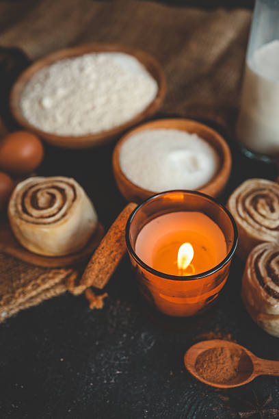 istock A cozy baking scene with cinnamon buns, a lit candle, flour, sugar, eggs, and milk on a dark surface, perfect for warm, rustic kitchen themes 2207948186