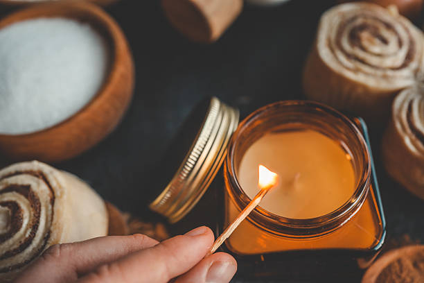 istock A hand lighting a candle in a cozy baking setup with cinnamon buns, flour, sugar, and eggs on a dark surface, ideal for warm kitchen scenes. 2207948187