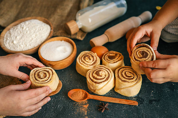 istock Children rolling cinnamon buns on a dark surface with flour, sugar, eggs, and milk, capturing a cozy baking scene, perfect for family cooking themes 2207948196