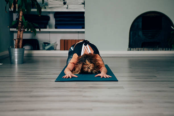 Yoga instructor performing child's pose on a mat in studio