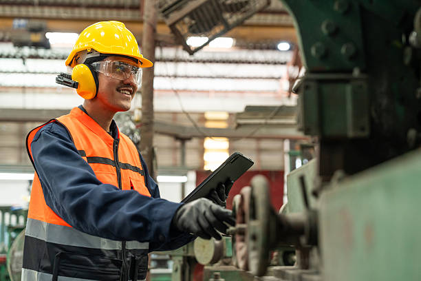 istock Confident engineer man with safety helmet standing analyzing with tablet in factory warehouse. Asian technician factory inspection and control machinery in industry factory. 2207952598