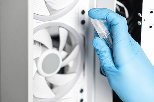 istock Technician in blue glove using spray bottle to clean cooling fan inside modern computer case 2207955757