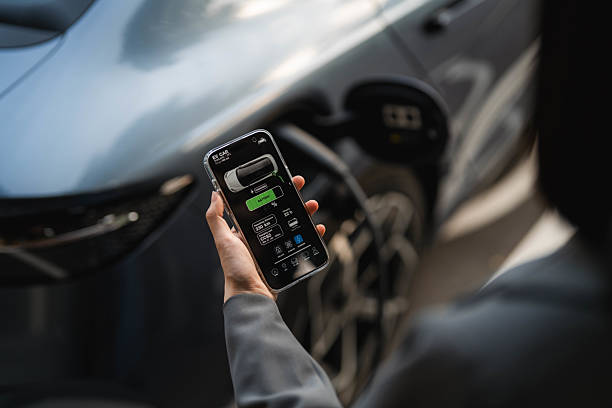 istock A woman standing at the EV charging station, using her smartphone while waiting for her electric vehicle to finish charging 2207959664