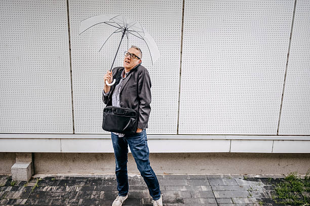 Businessman going home after work on rainy day holding umbrella