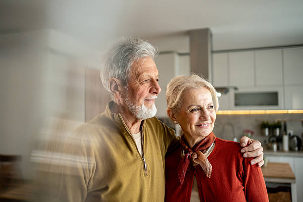 istock Happy senior couple embracing and looking out window in kitchen 2207961849