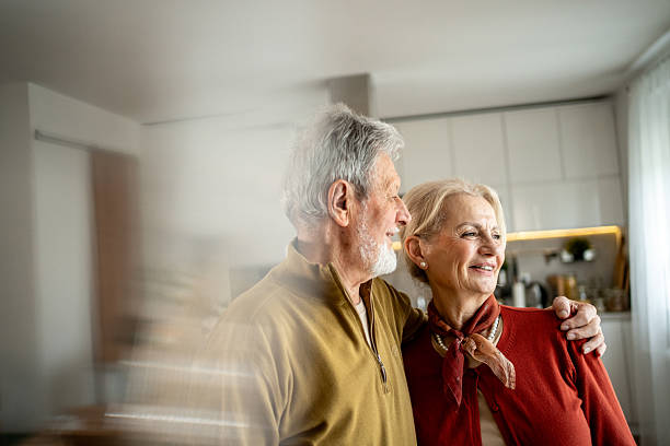 istock Happy senior couple embracing and looking out window in kitchen 2207961897