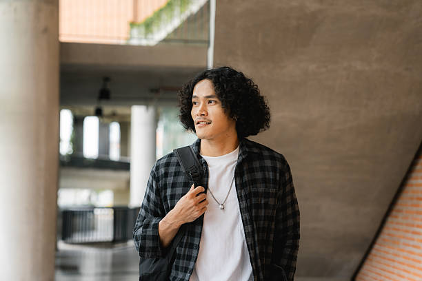 istock University student walking through a campus building, holding a digital tablet as he heads to class 2207964291