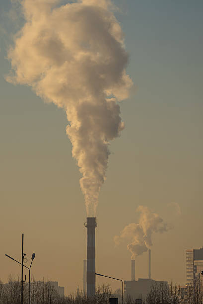 istock Industrial chimneys releasing smoke into atmosphere at sunset 2207964457