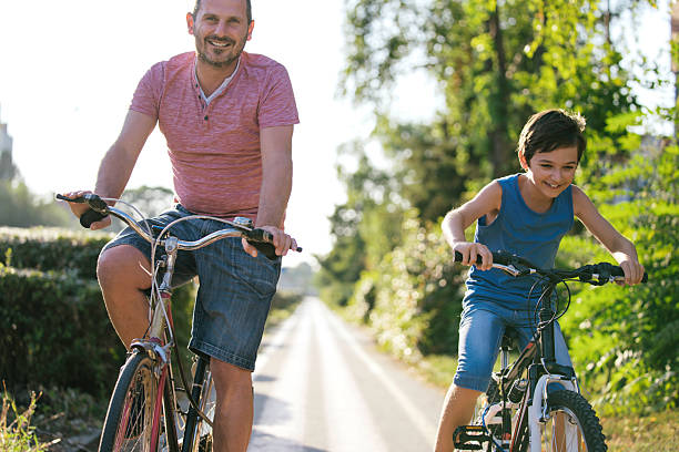 istock Father and Son Cycling Together With Great Smiles 2207964564